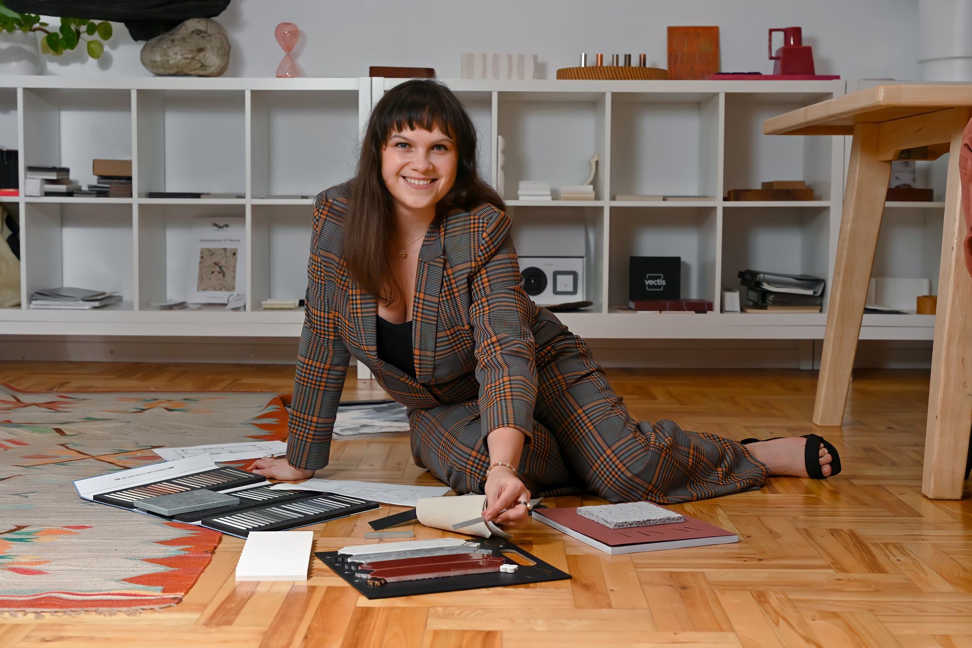 Patrycja Duda, projektantka wnętrz z Krakowa, siedzi na podłodze wśród próbek materiałów i kolorów do projektu wnętrza